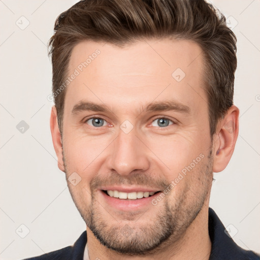 Joyful white young-adult male with short  brown hair and grey eyes