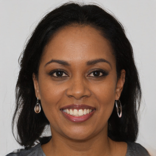 Joyful black young-adult female with long  brown hair and brown eyes