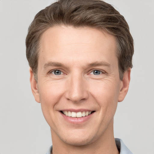 Joyful white young-adult male with short  brown hair and grey eyes