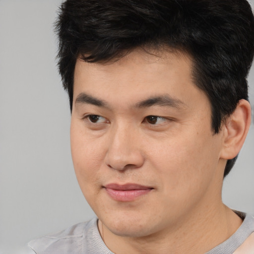 Joyful asian young-adult male with short  brown hair and brown eyes