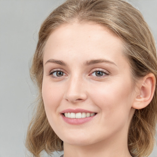 Joyful white young-adult female with long  brown hair and blue eyes