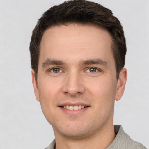 Joyful white young-adult male with short  brown hair and grey eyes