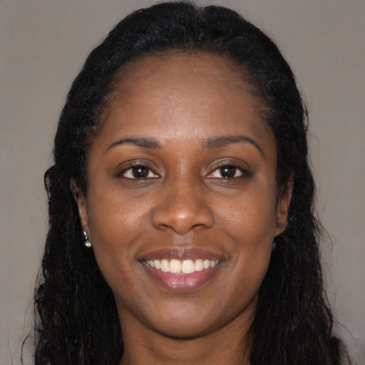 Joyful black young-adult female with long  black hair and brown eyes
