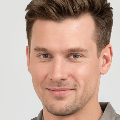 Joyful white young-adult male with short  brown hair and grey eyes