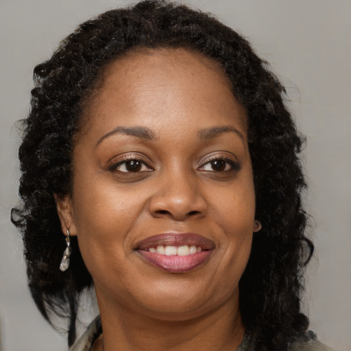 Joyful black adult female with long  brown hair and brown eyes
