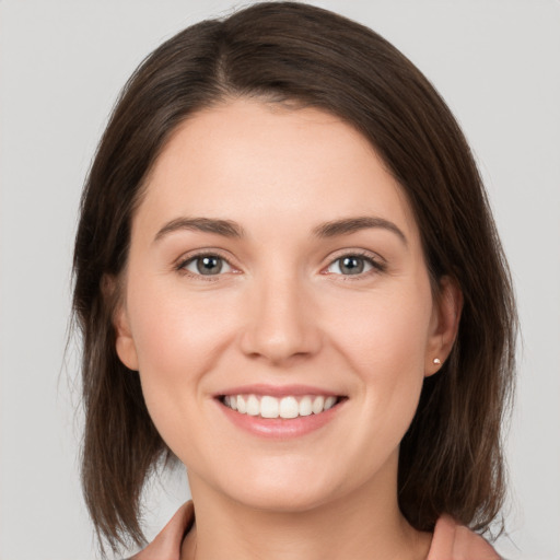 Joyful white young-adult female with medium  brown hair and grey eyes