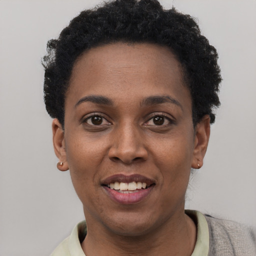 Joyful black young-adult female with short  black hair and brown eyes