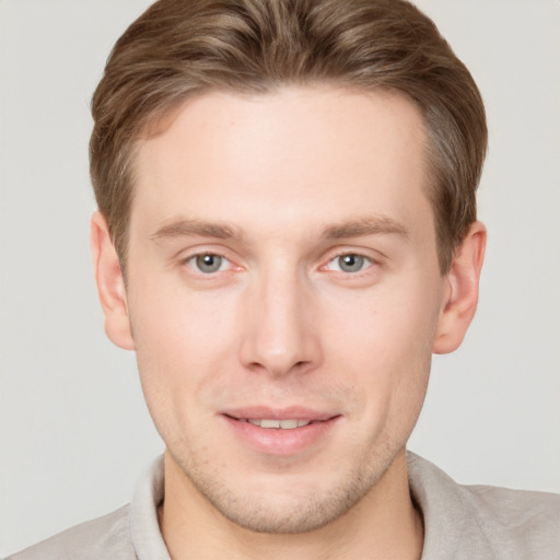 Joyful white young-adult male with short  brown hair and grey eyes