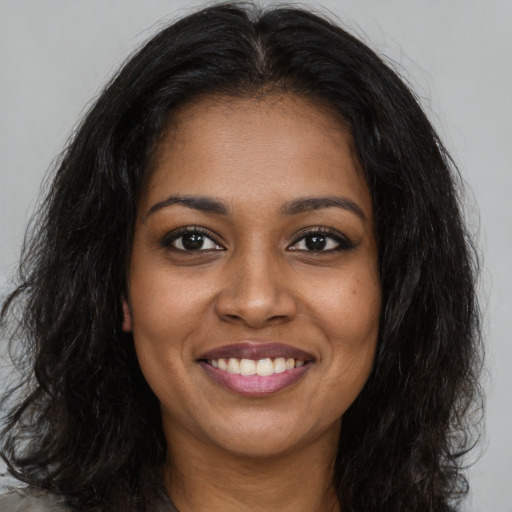 Joyful black young-adult female with long  brown hair and brown eyes