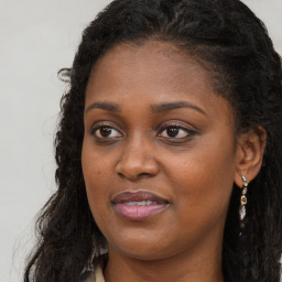 Joyful black young-adult female with long  brown hair and brown eyes