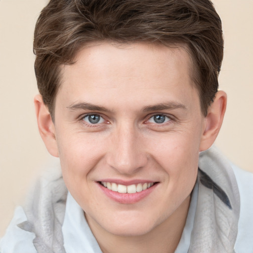 Joyful white young-adult male with short  brown hair and grey eyes