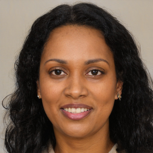 Joyful black adult female with long  brown hair and brown eyes