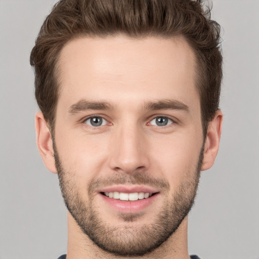 Joyful white young-adult male with short  brown hair and grey eyes