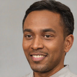 Joyful black young-adult male with short  black hair and brown eyes