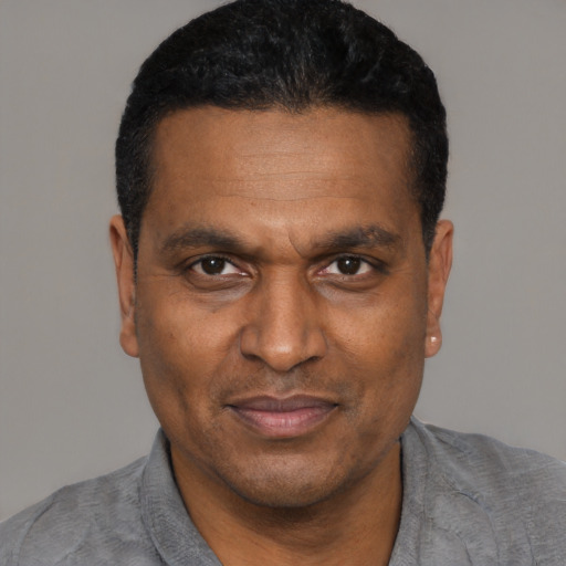 Joyful black adult male with short  black hair and brown eyes