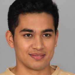 Joyful latino young-adult male with short  brown hair and brown eyes