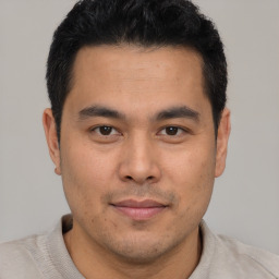 Joyful latino young-adult male with short  brown hair and brown eyes