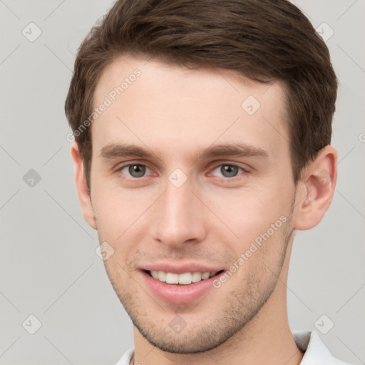 Joyful white young-adult male with short  brown hair and grey eyes