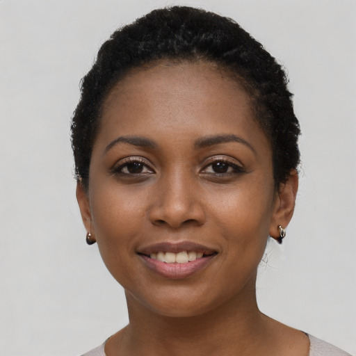 Joyful black young-adult female with short  black hair and brown eyes