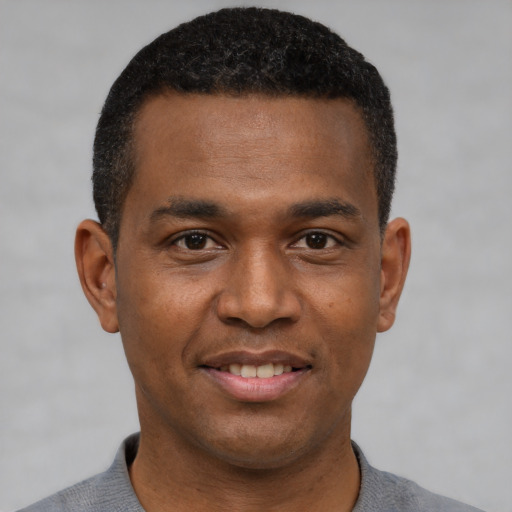 Joyful black young-adult male with short  black hair and brown eyes