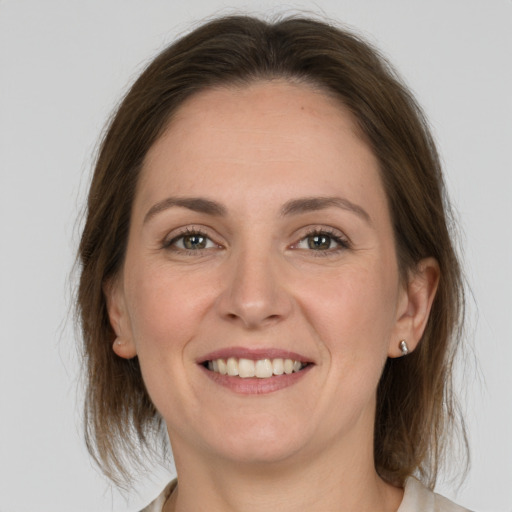 Joyful white young-adult female with medium  brown hair and grey eyes