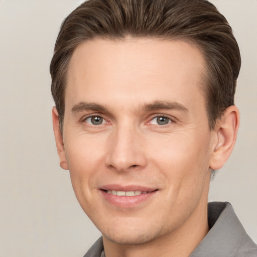 Joyful white young-adult male with short  brown hair and grey eyes