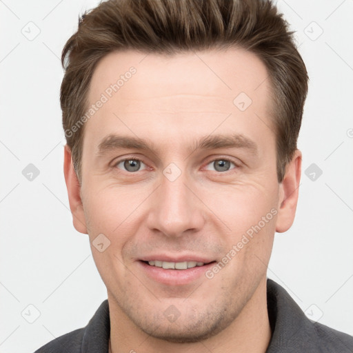 Joyful white young-adult male with short  brown hair and grey eyes