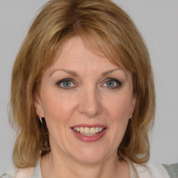 Joyful white adult female with medium  brown hair and blue eyes