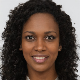 Joyful black young-adult female with long  brown hair and brown eyes