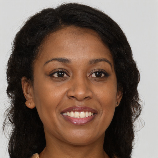 Joyful black young-adult female with long  brown hair and brown eyes