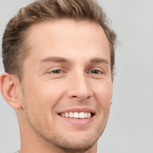 Joyful white young-adult male with short  brown hair and grey eyes