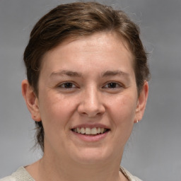 Joyful white young-adult female with medium  brown hair and grey eyes