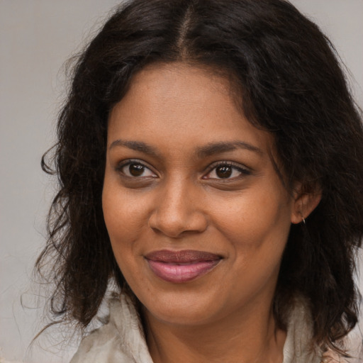 Joyful black young-adult female with long  brown hair and brown eyes
