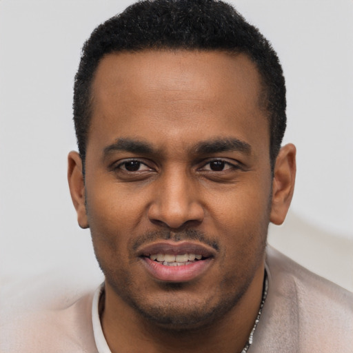 Joyful black young-adult male with short  black hair and brown eyes