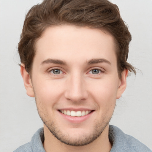 Joyful white young-adult male with short  brown hair and blue eyes