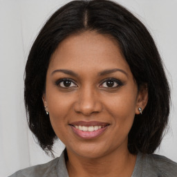 Joyful black young-adult female with long  brown hair and brown eyes