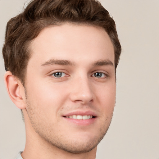 Joyful white young-adult male with short  brown hair and grey eyes