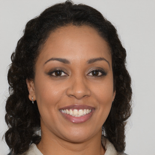 Joyful black young-adult female with long  brown hair and brown eyes