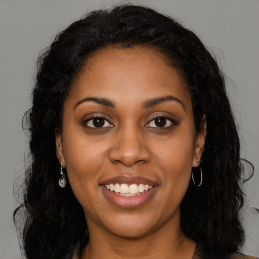 Joyful black young-adult female with long  black hair and brown eyes