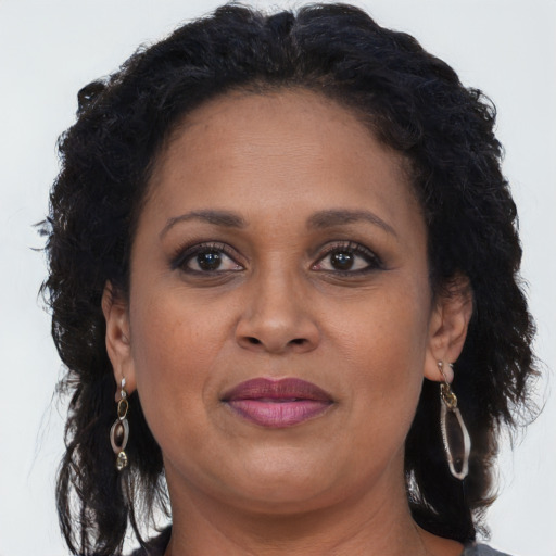 Joyful black adult female with long  brown hair and brown eyes