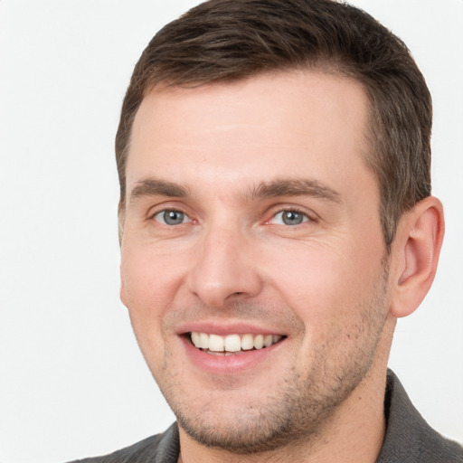 Joyful white young-adult male with short  brown hair and grey eyes