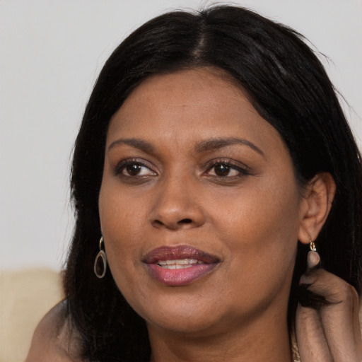 Joyful black adult female with long  brown hair and brown eyes