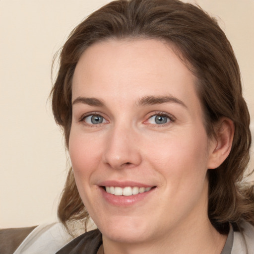 Joyful white young-adult female with medium  brown hair and grey eyes