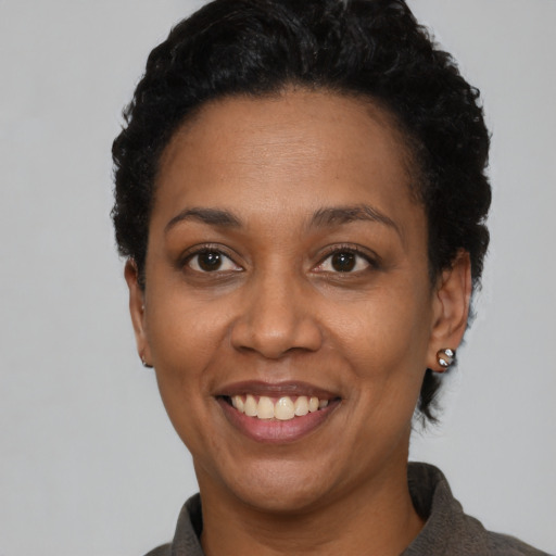 Joyful black adult female with short  black hair and brown eyes