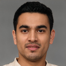 Joyful latino young-adult male with short  black hair and brown eyes