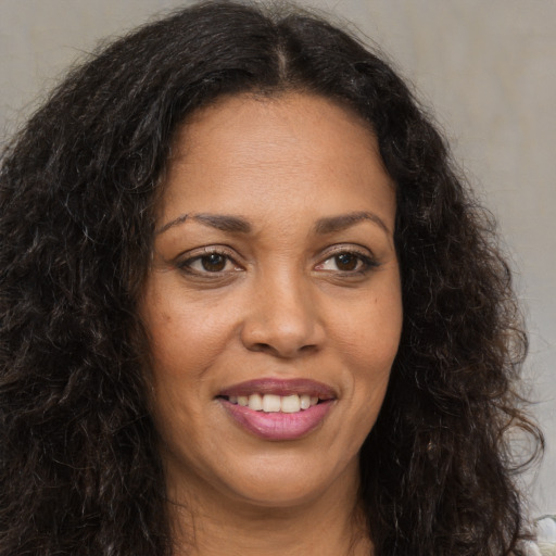 Joyful black young-adult female with long  brown hair and brown eyes