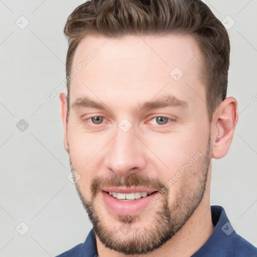 Joyful white young-adult male with short  brown hair and grey eyes