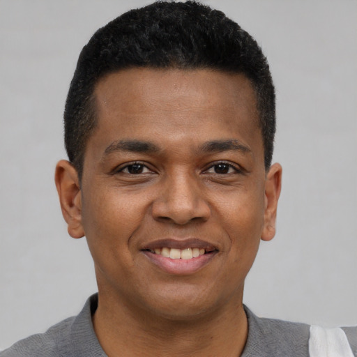 Joyful black young-adult male with short  brown hair and brown eyes