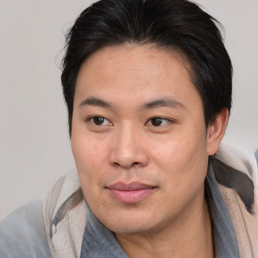 Joyful asian young-adult male with medium  brown hair and brown eyes