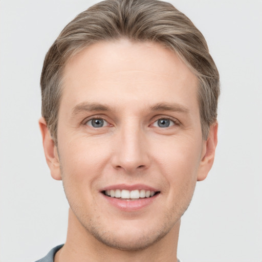 Joyful white young-adult male with short  brown hair and grey eyes